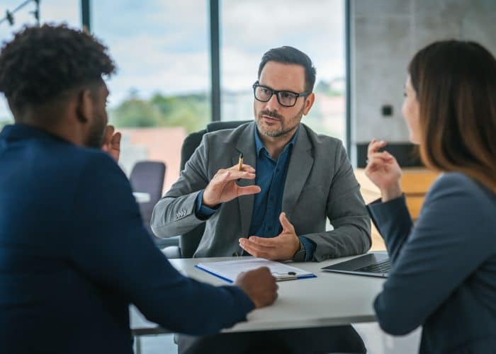 Financial adviser discussing contract with diverse couple in office meeting